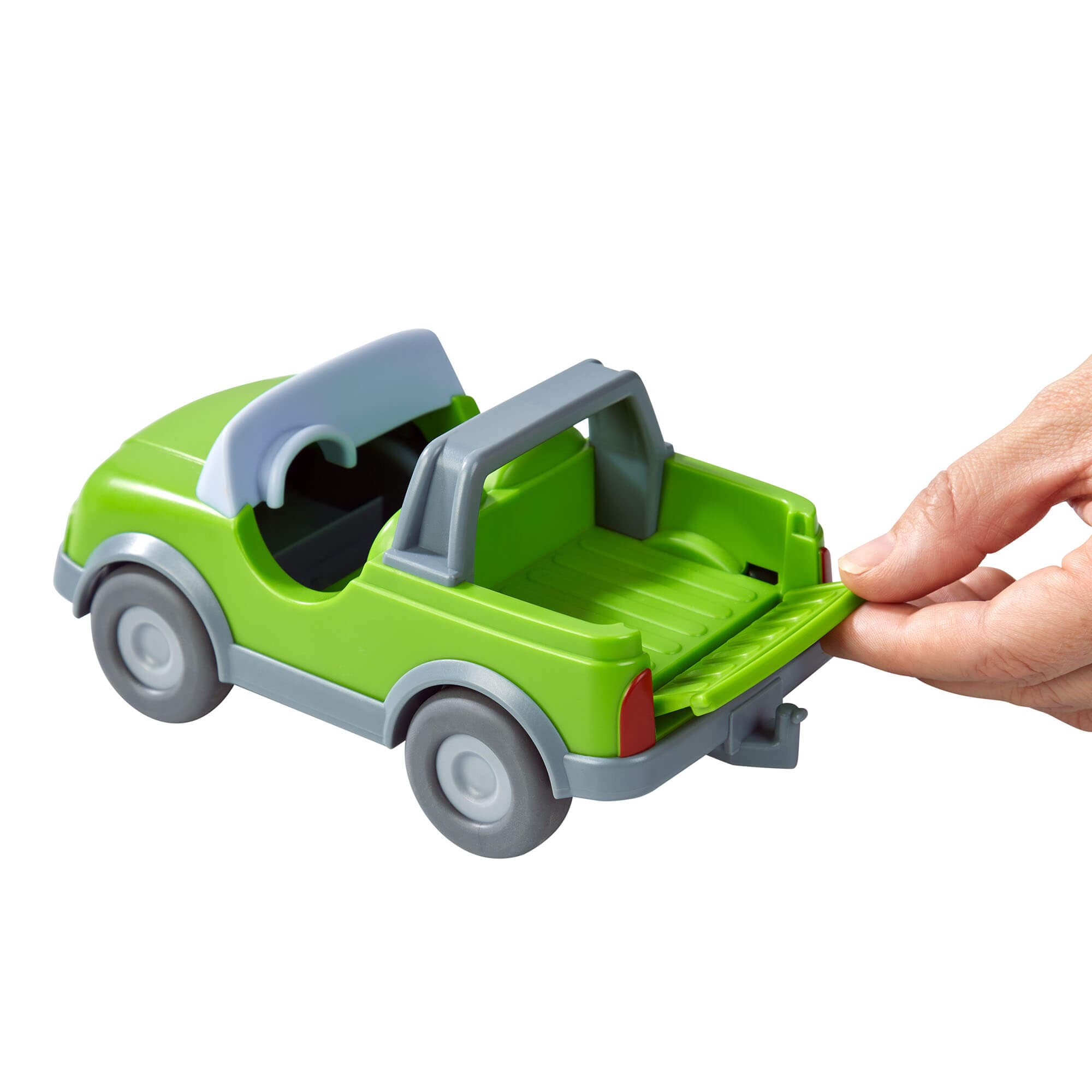 Green toy car with an open trunk being held by a hand on a white background