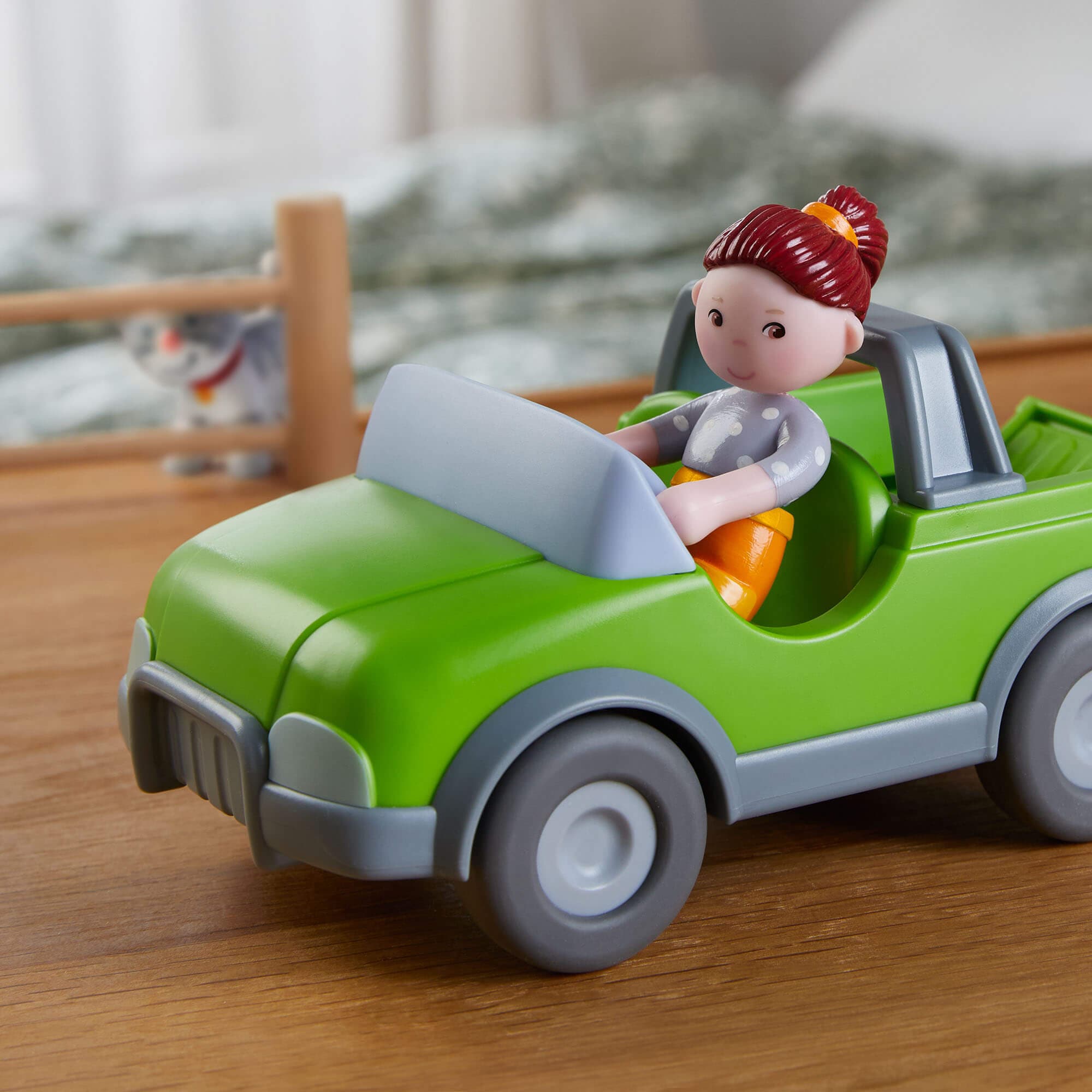 Toy car with a figurine of a child driving on a wooden surface
