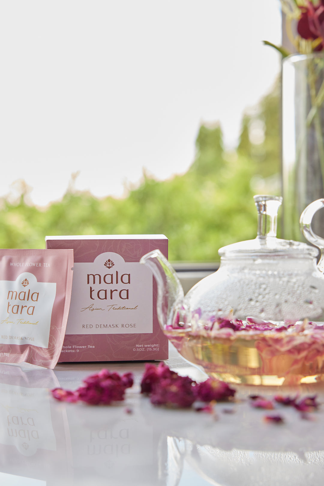 Mala Tara tea packaging with a teapot and tea bags on a table outdoors.