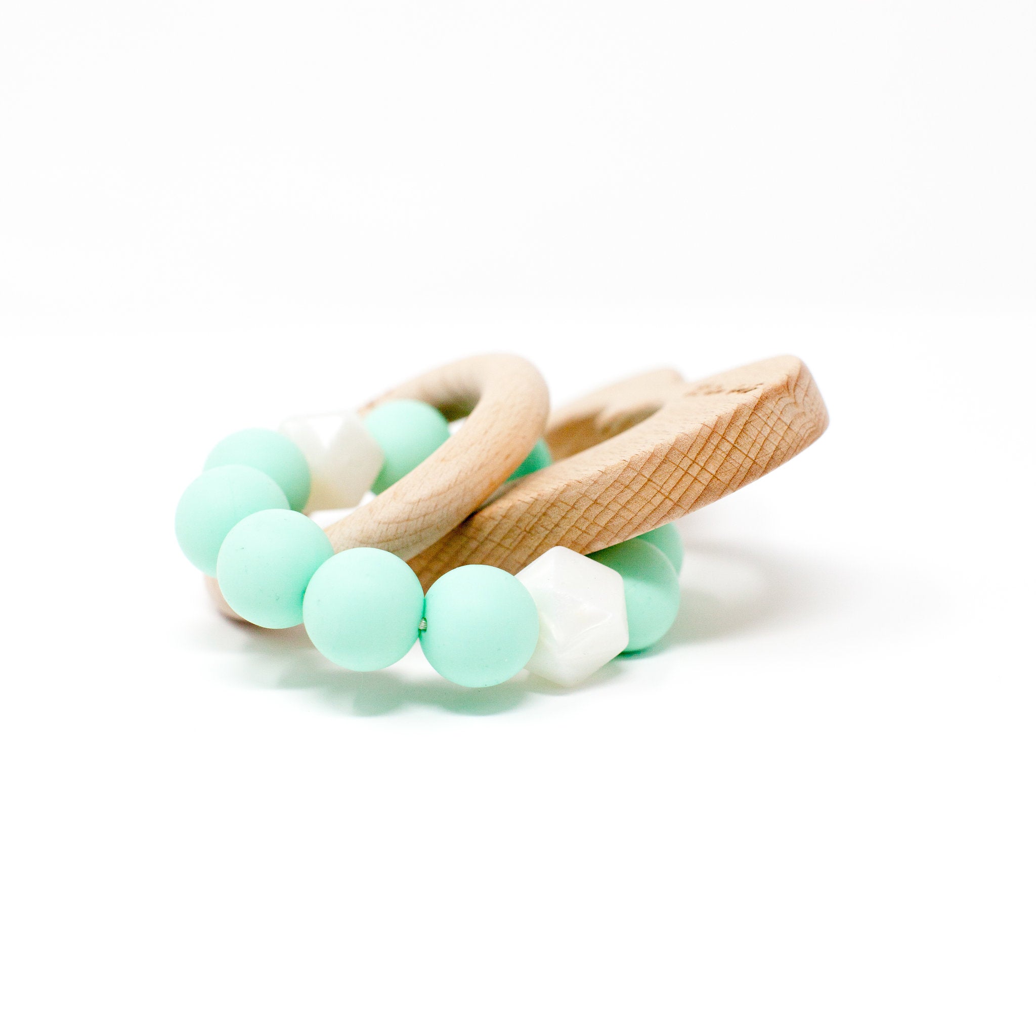 Teething ring with mint green beads and wooden handle on a white background