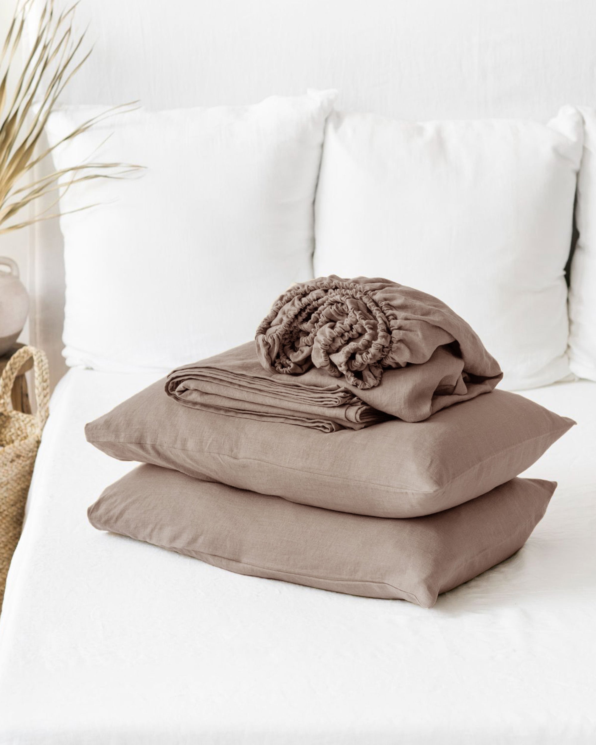 Stack of brown folded clothes on a white sofa with a neutral background