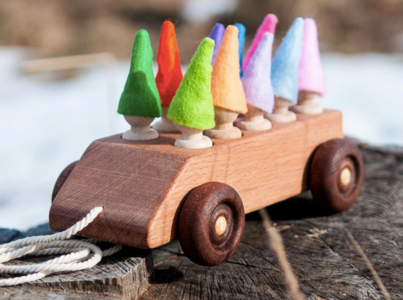 Wooden toy car with colorful felt trees on a wooden surface