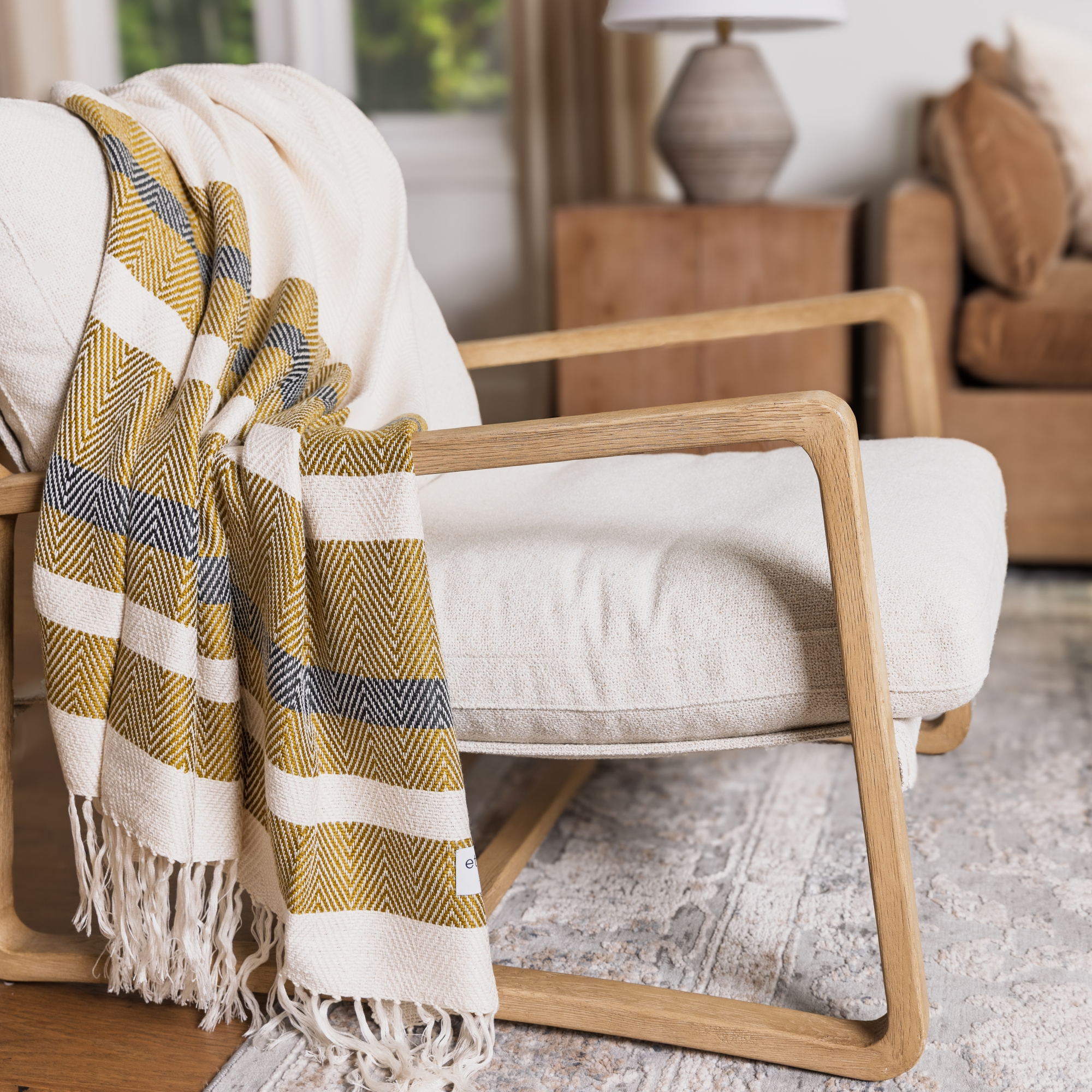 Yellow and white striped blanket draped over a wooden chair in a cozy living room.