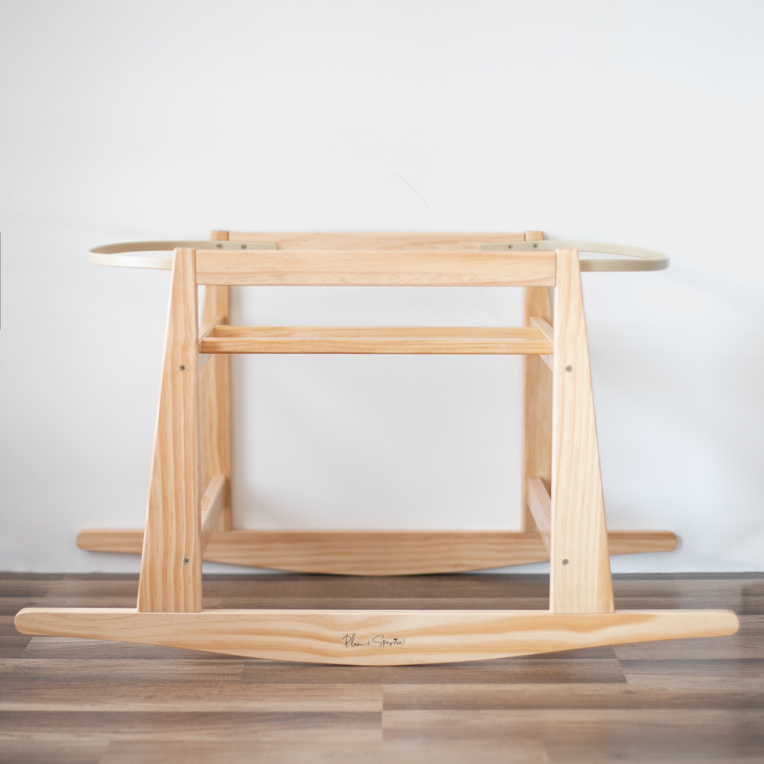 Wooden baby rocker on a wooden floor with a white wall background
