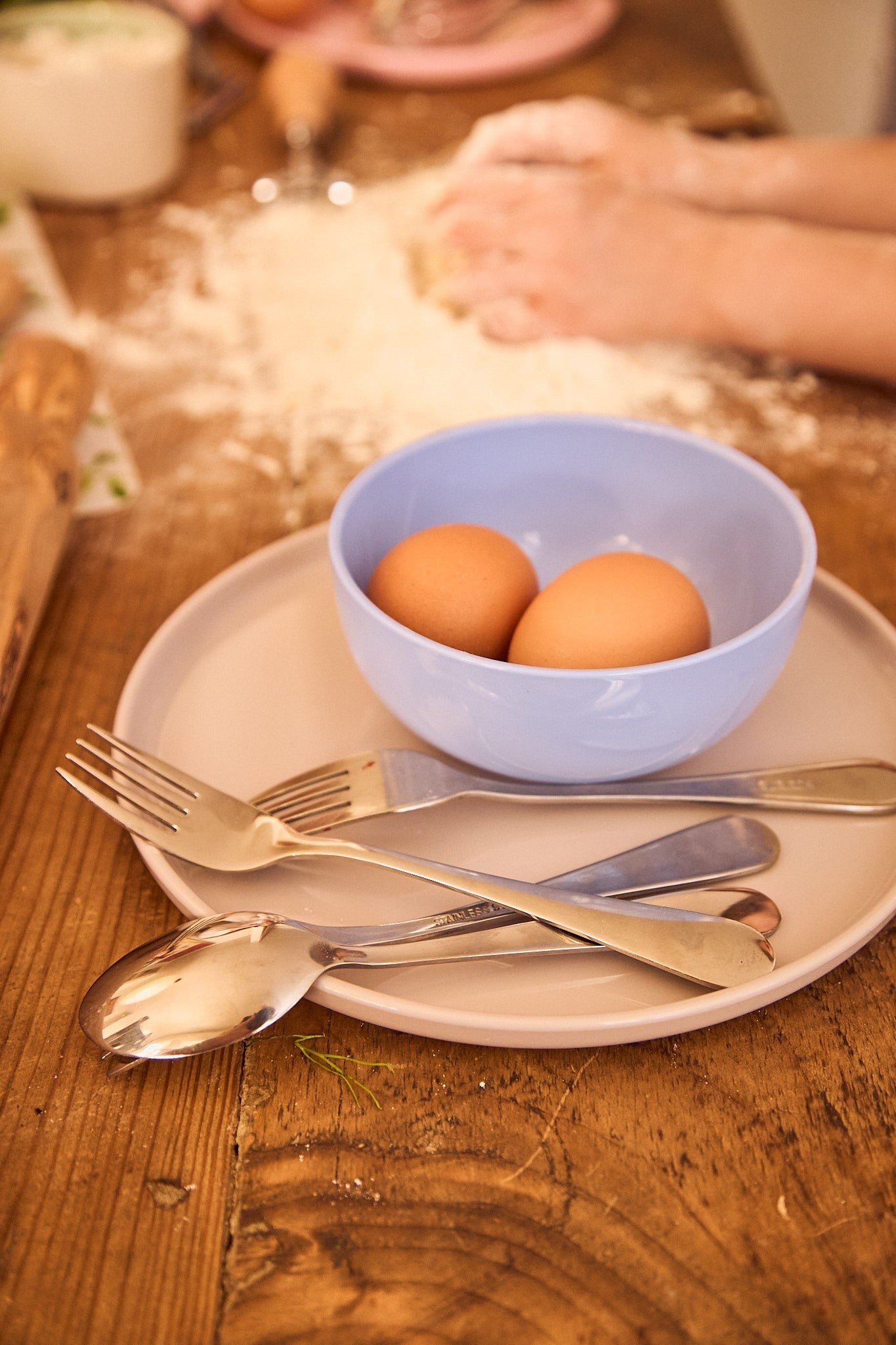 Bowl of eggs on a plate with cutlery on a wooden table