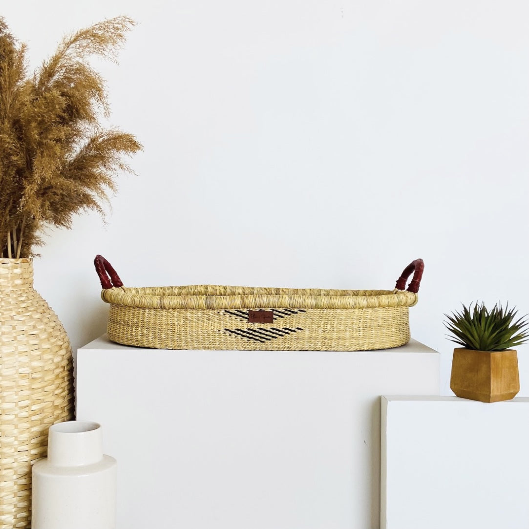 Decorative items including a woven basket, vase, and plant on a white surface with a light blue background.
