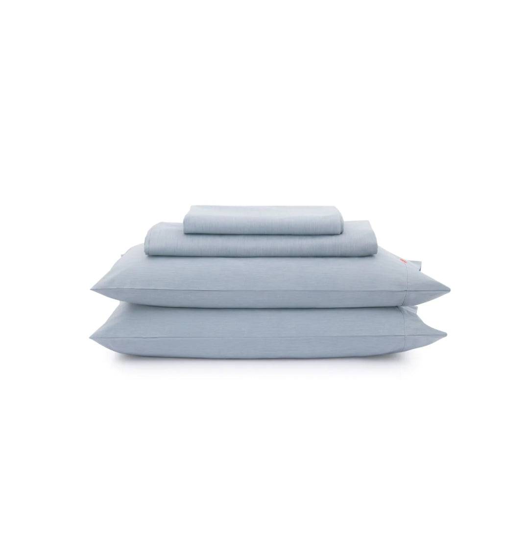 Set of light blue bedding including a duvet, two pillows, and a fitted sheet on a white background.