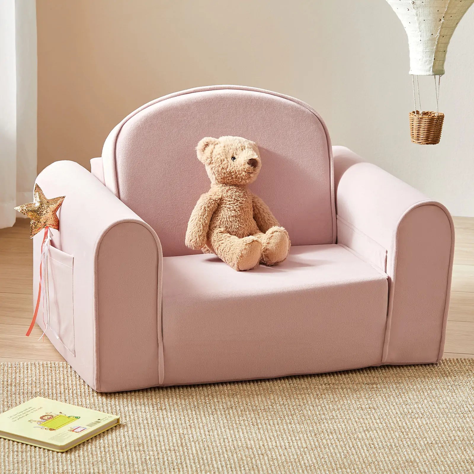 Pink children's chair with a teddy bear on a carpeted floor.