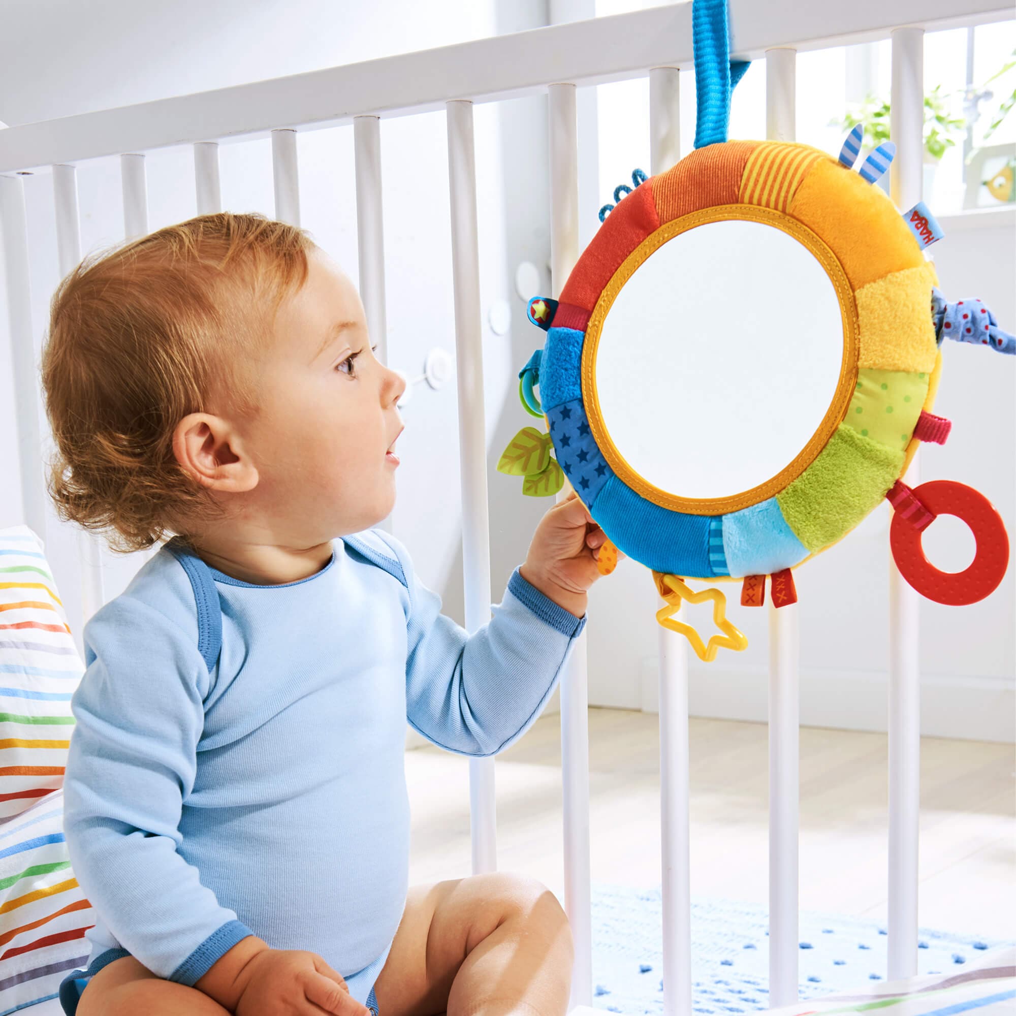 Baby playing with a colorful toy in a crib