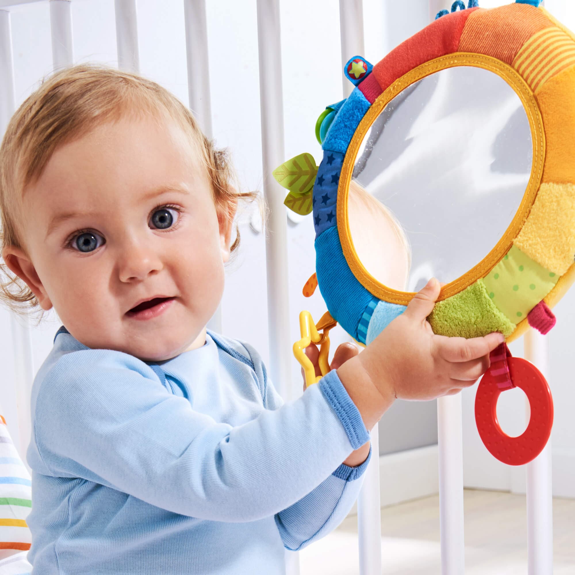 Baby holding a colorful toy with a mirror