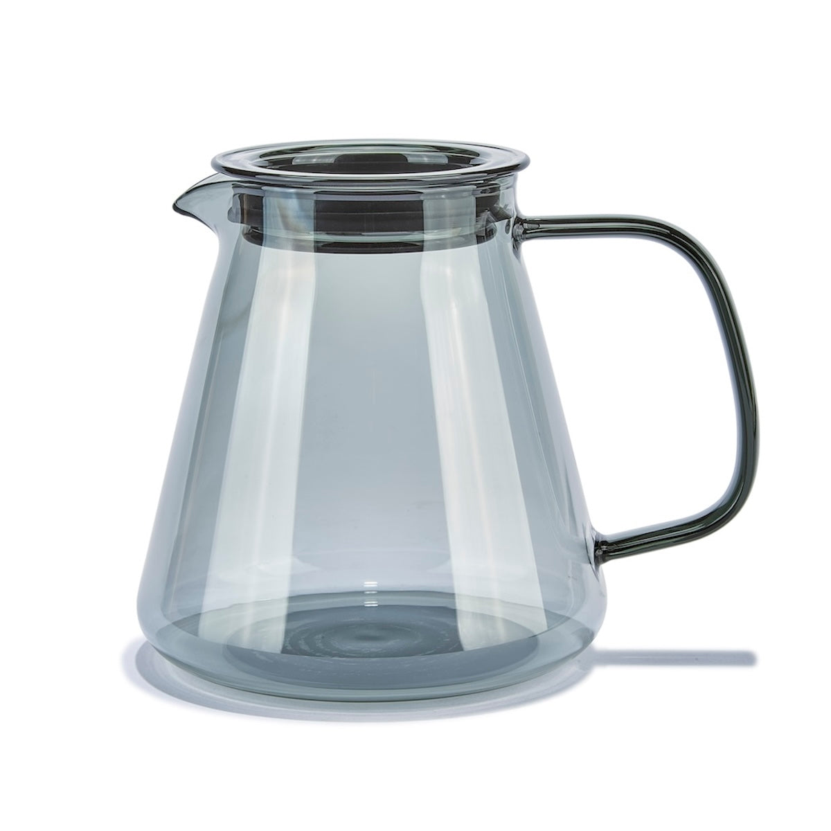 Clear glass pitcher with black handle on a white background