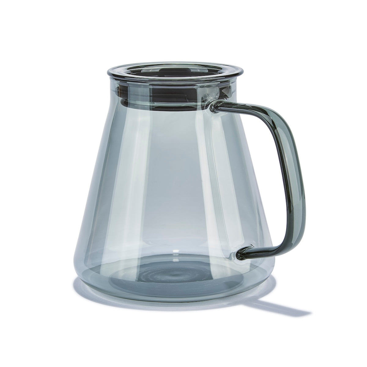 Clear glass carafe with black handle on a white background