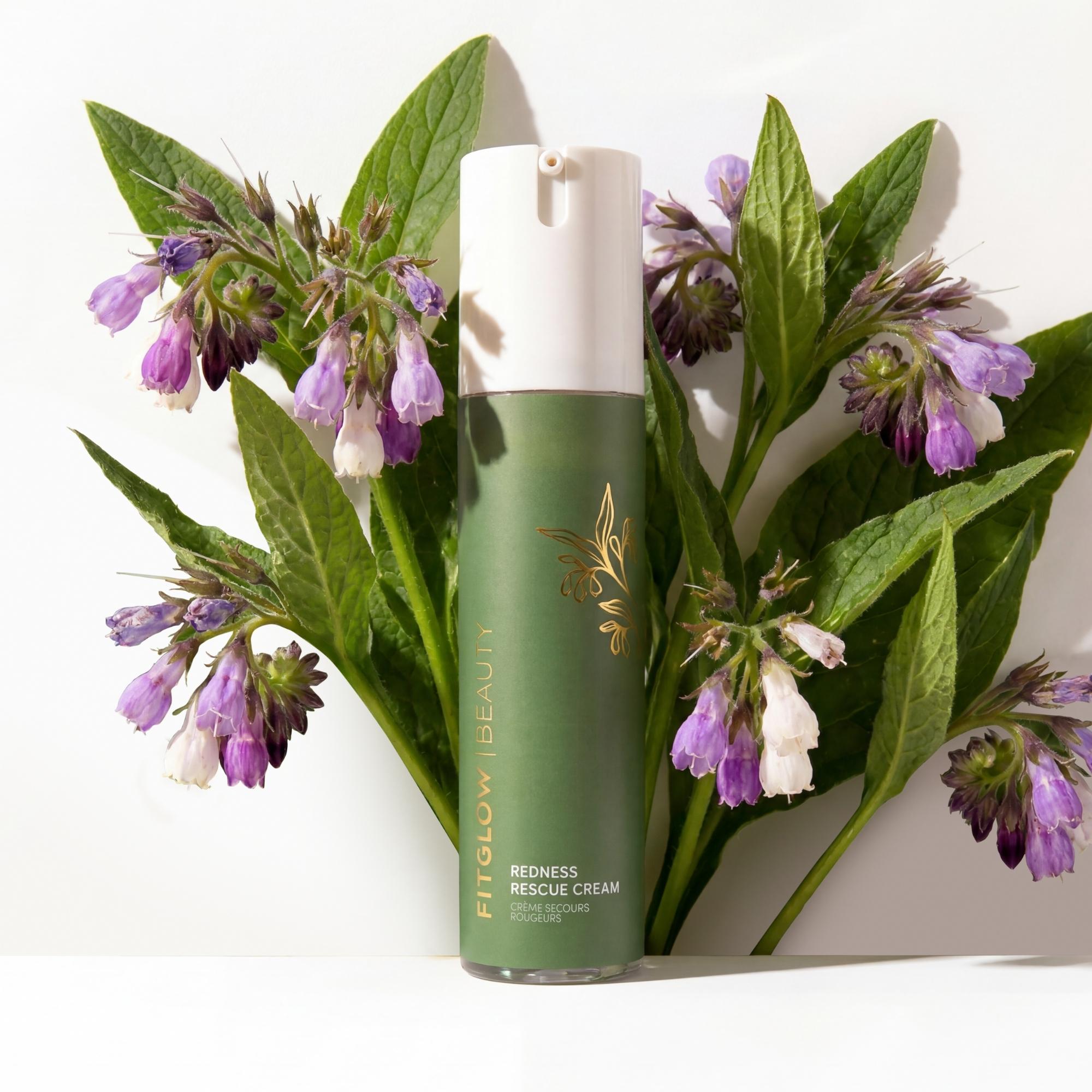 Green skincare bottle with white cap on a white background with green leaves and purple flowers.