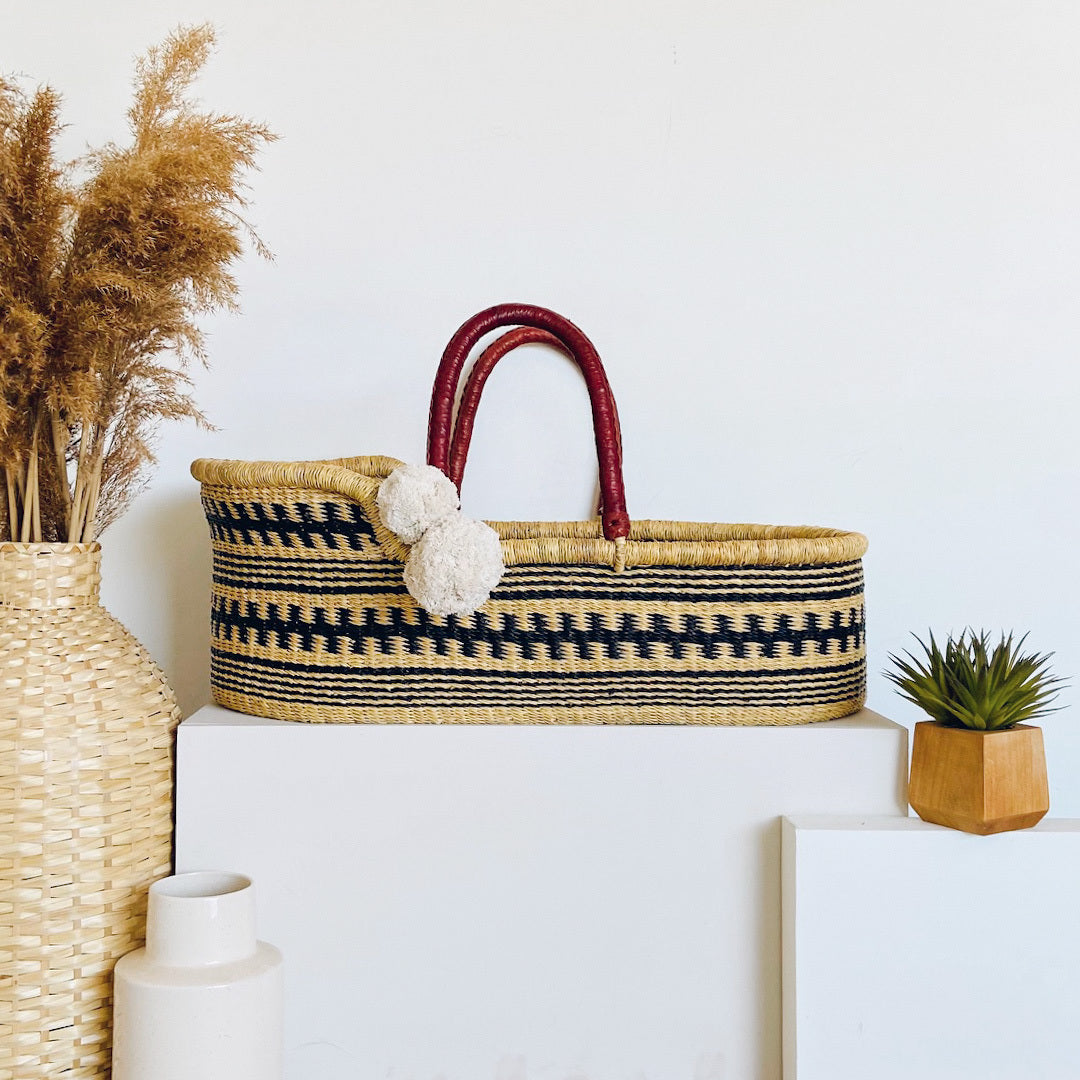 Woven basket with red handles on a white surface, surrounded by decorative items.