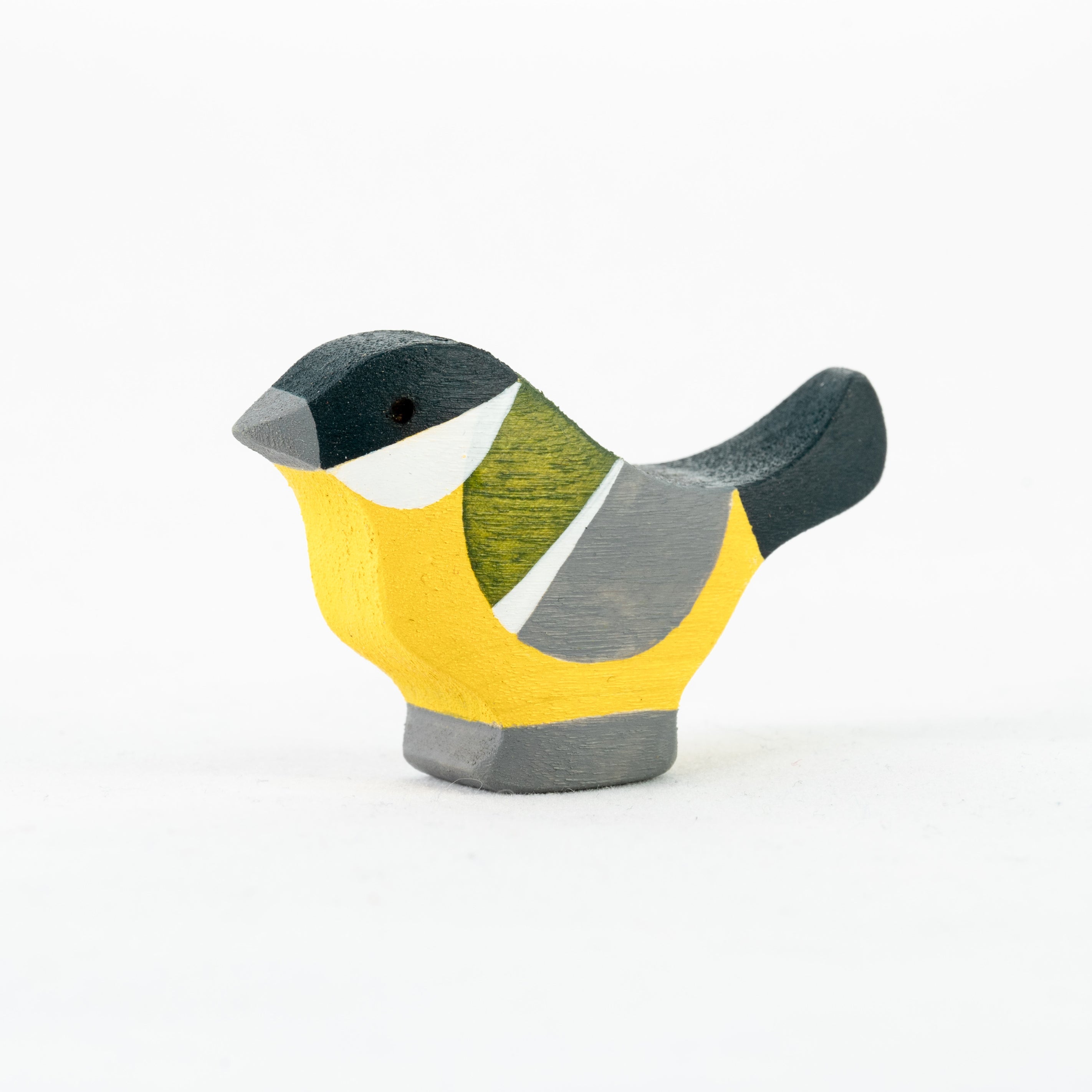 Wooden bird figurine with yellow body, gray wings, and white face on a white background