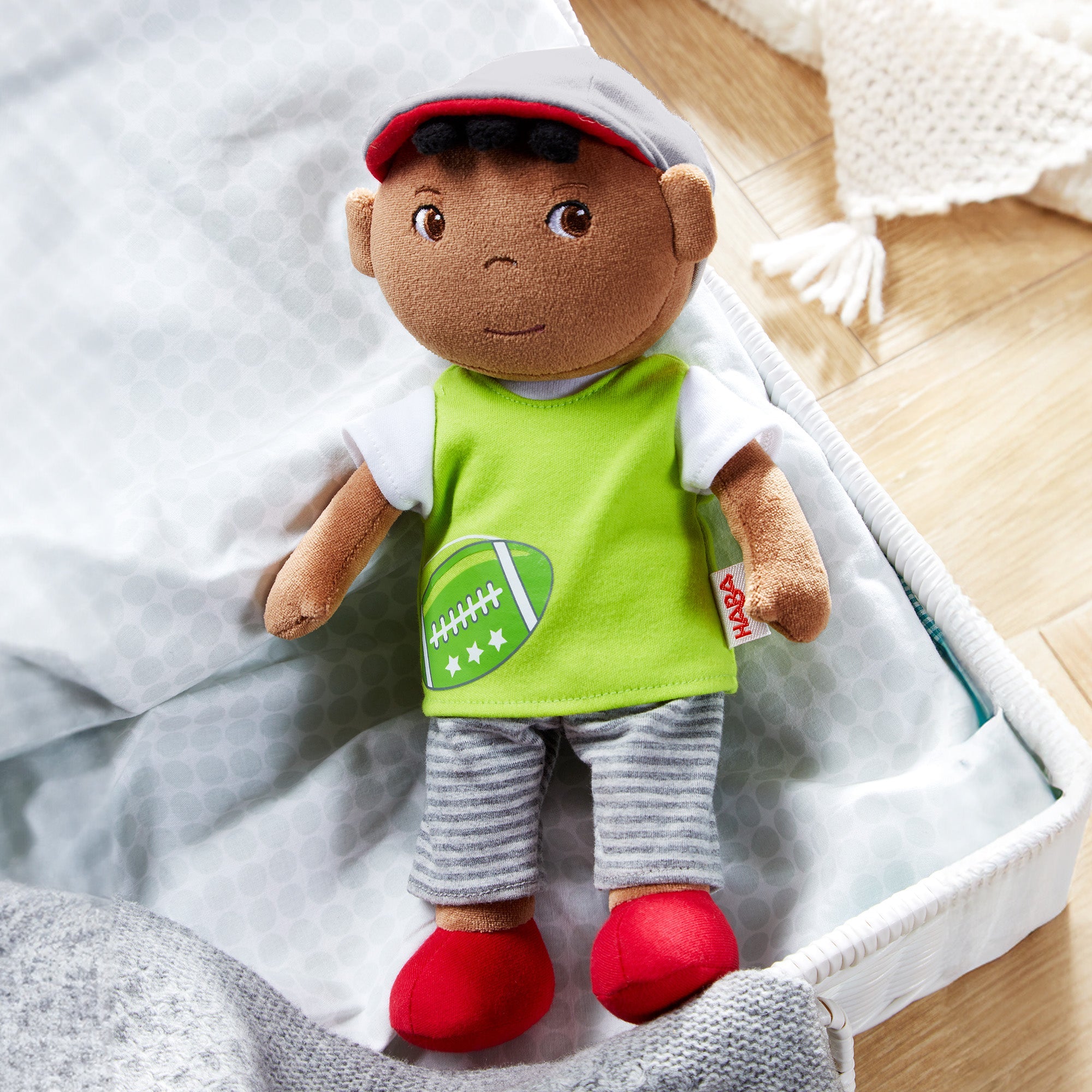 Plush toy with a green shirt and red shoes on a bed