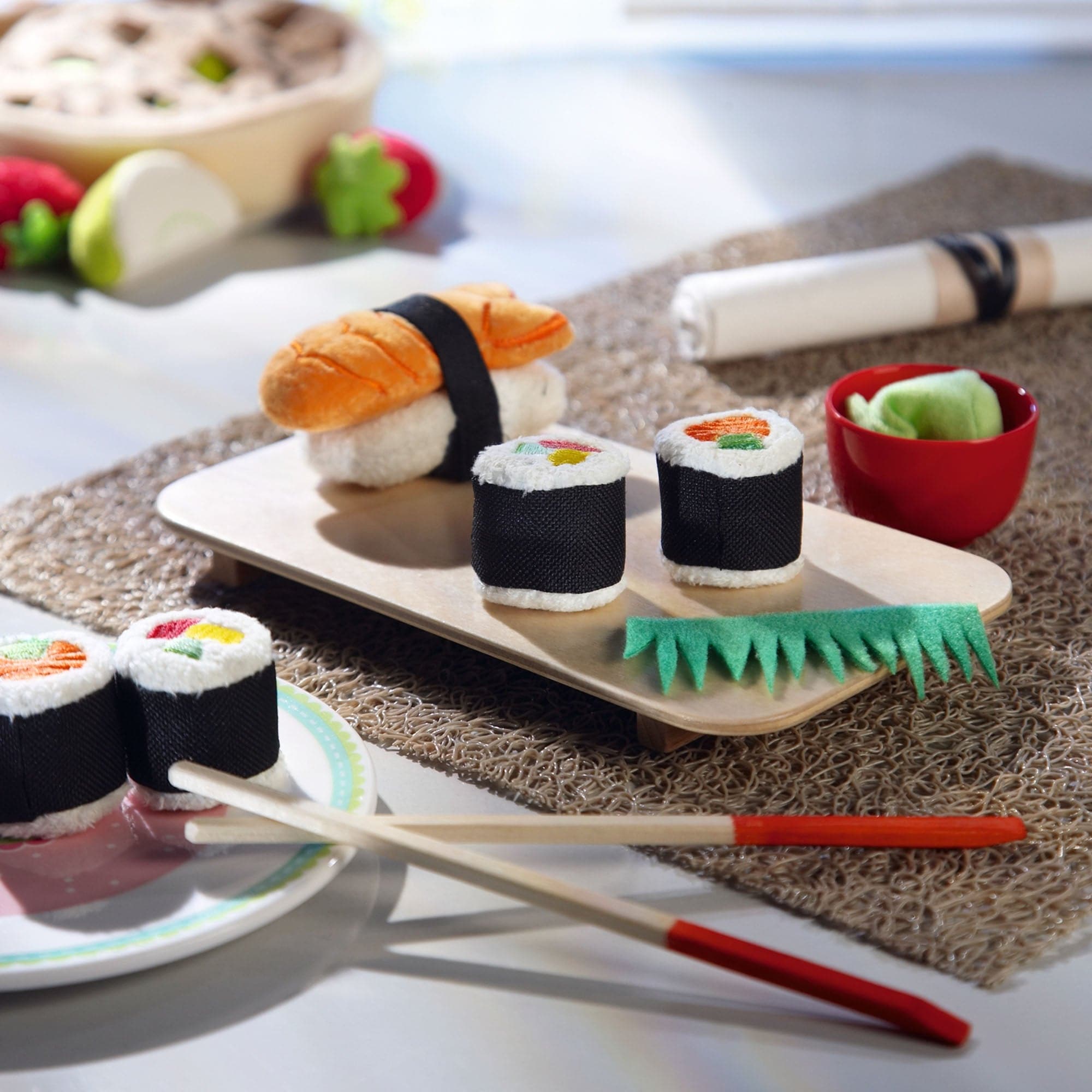 Toy sushi set with chopsticks on a textured surface