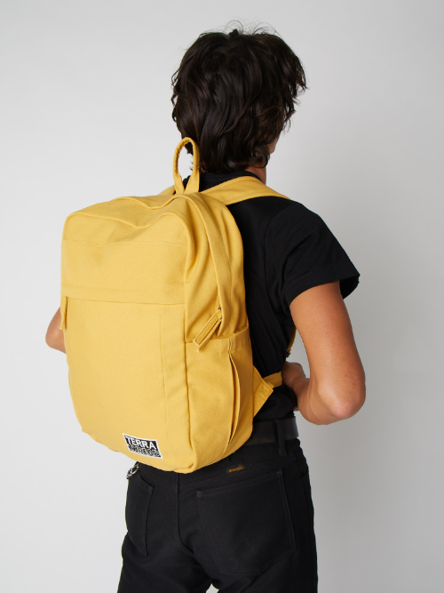 Person wearing a yellow backpack on a plain background