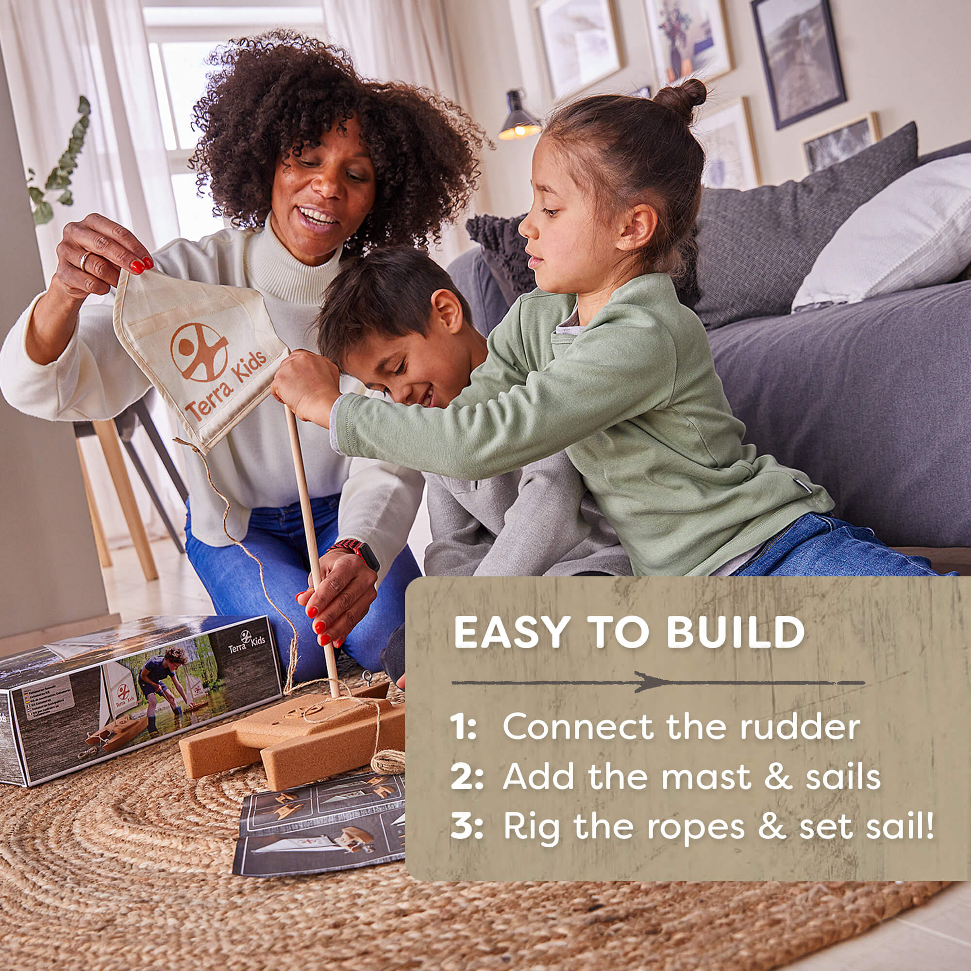 Woman and two children playing with a toy sailboat set in a living room.