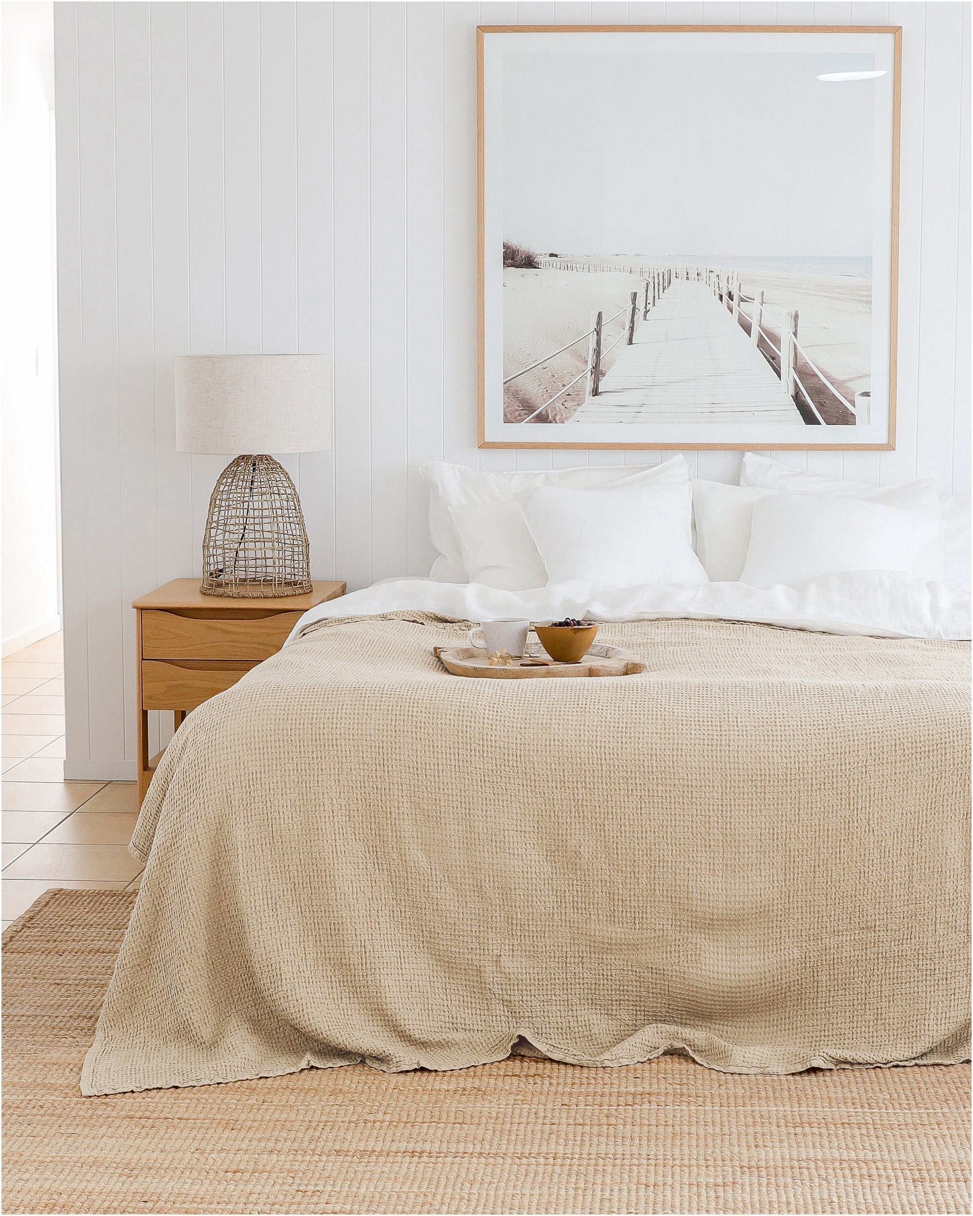 Neatly made bed with beige comforter in a bedroom setting.