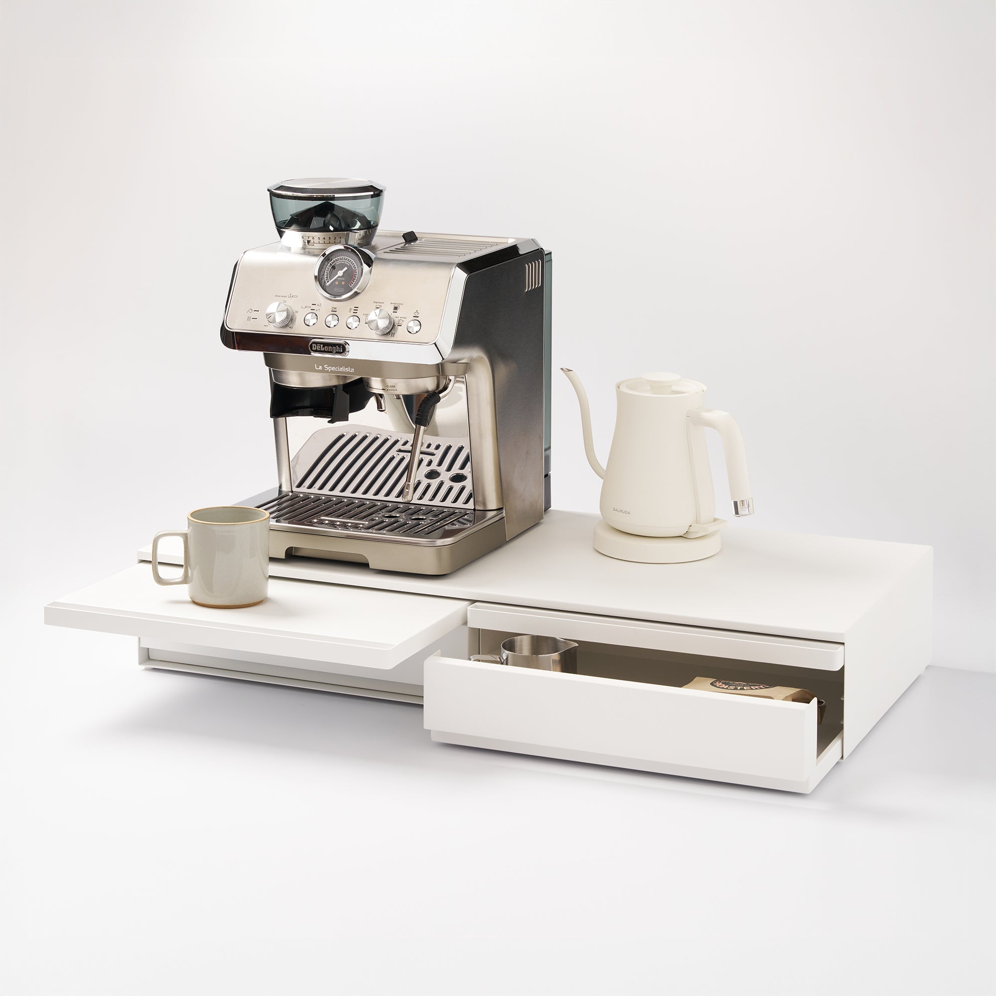 Espresso machine on a white surface with a drawer and cups.
