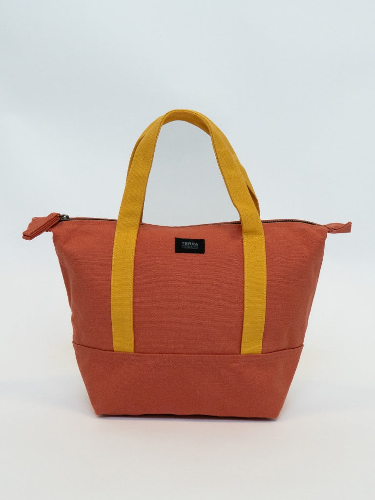 Orange tote bag with yellow handles on a light gray background