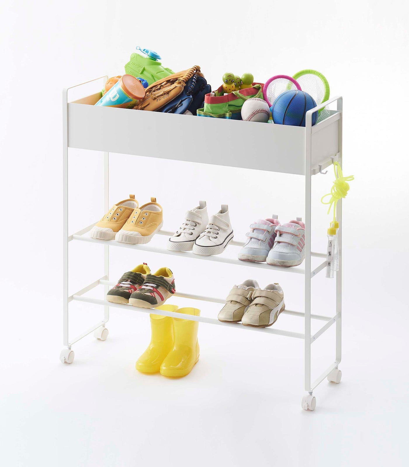 White metal rolling cart with children's shoes, toys, and boots on a white background