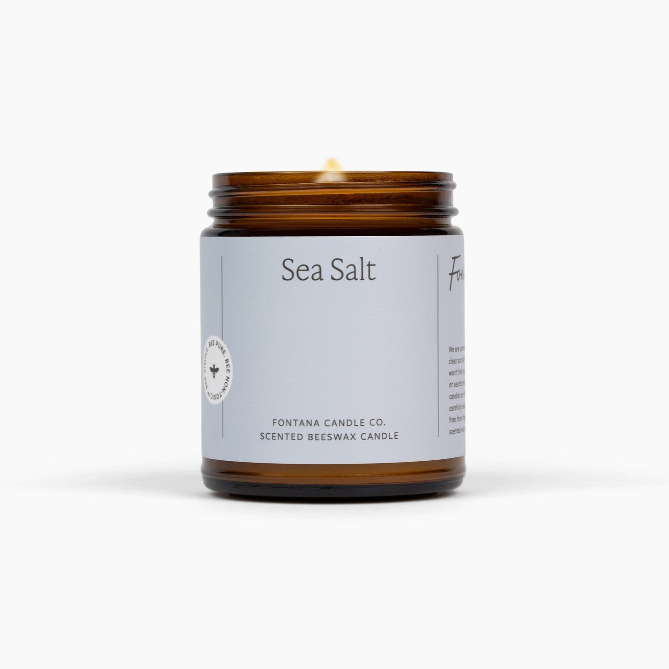 Beeswax candle in an amber jar with a gray label on a white background