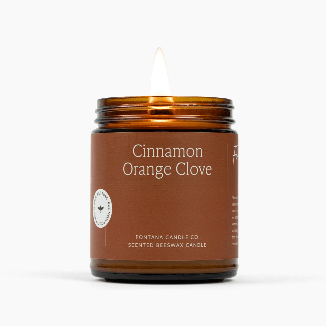 Candle in an amber jar labeled 'Cinnamon Orange Clove' by Fontana Candle Co on a white background