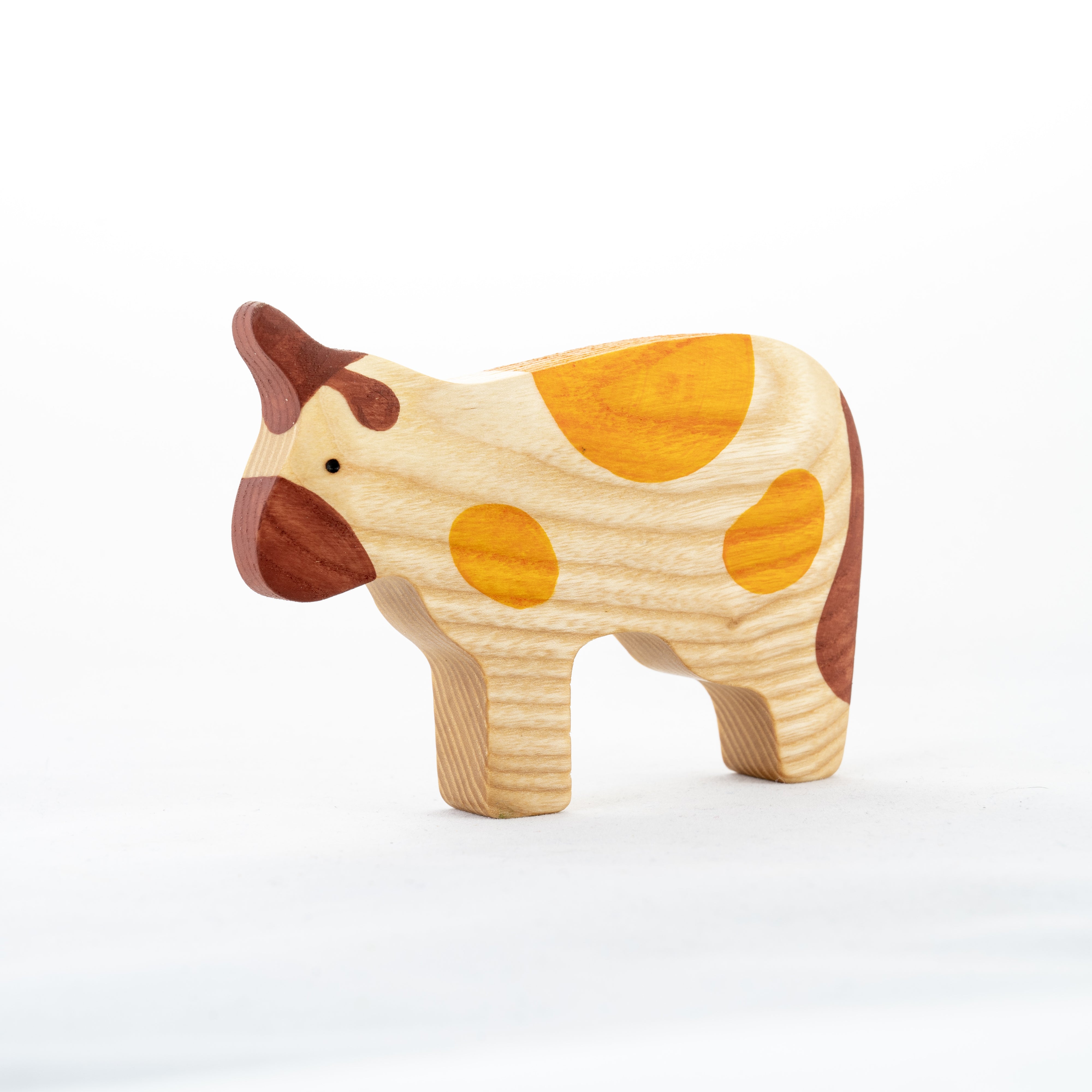 Wooden cow toy with brown and yellow spots on a white background