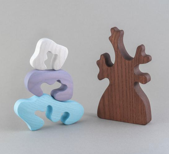 Three wooden sculptures in different colors on a gray background