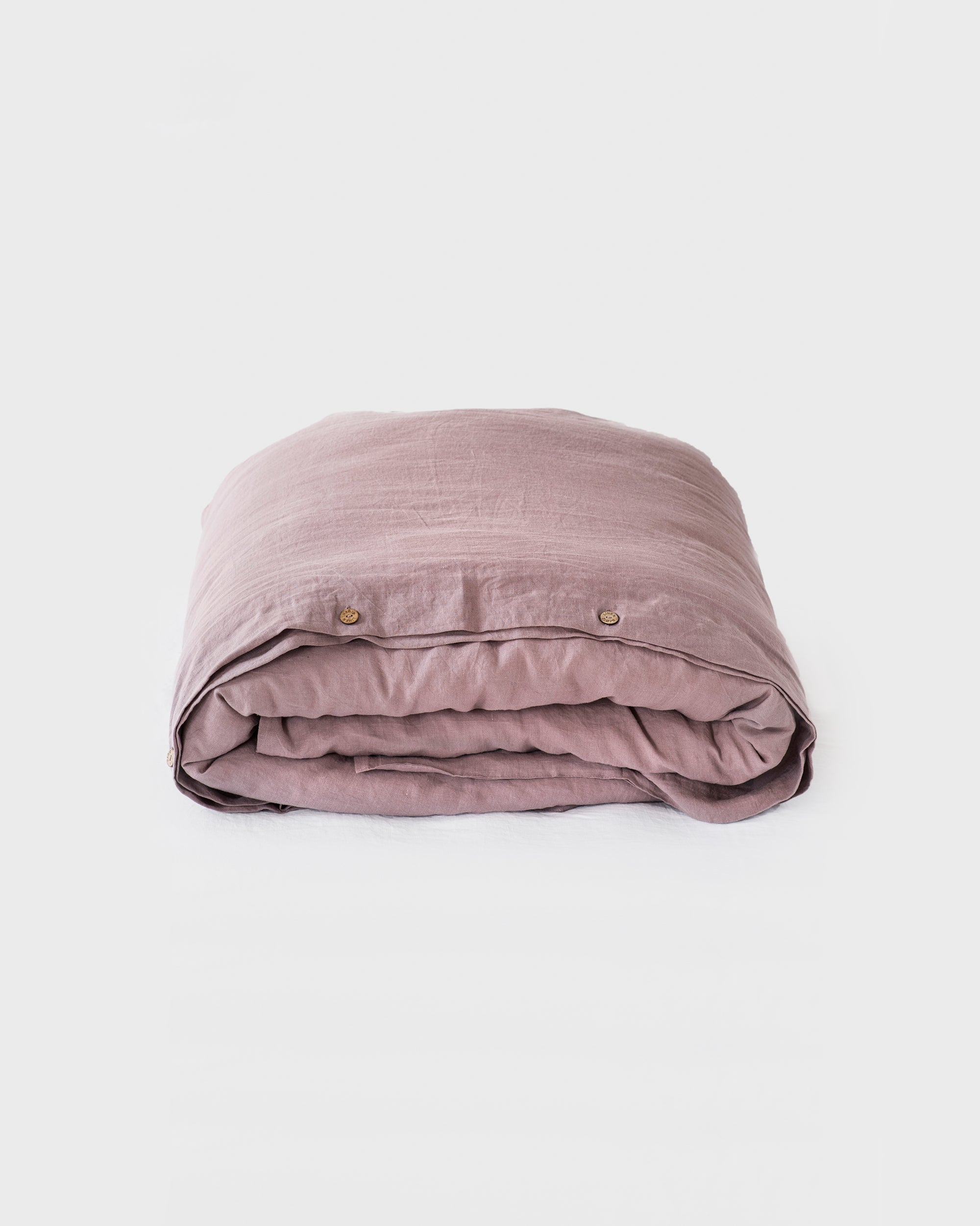 Folded pink blanket with buttons on a white background