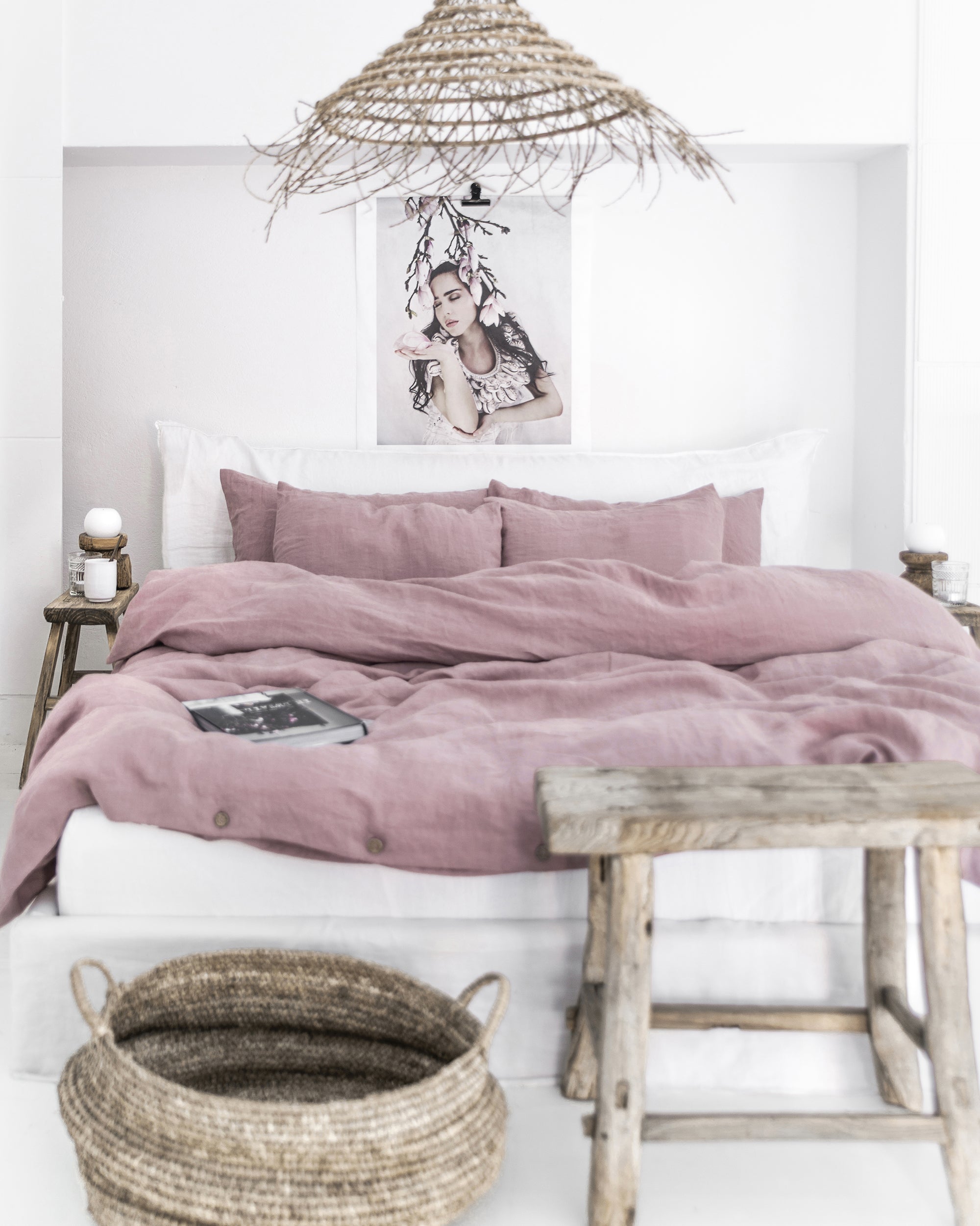 Bed with pink bedding and wooden furniture in a room with a white wall and decorative elements.