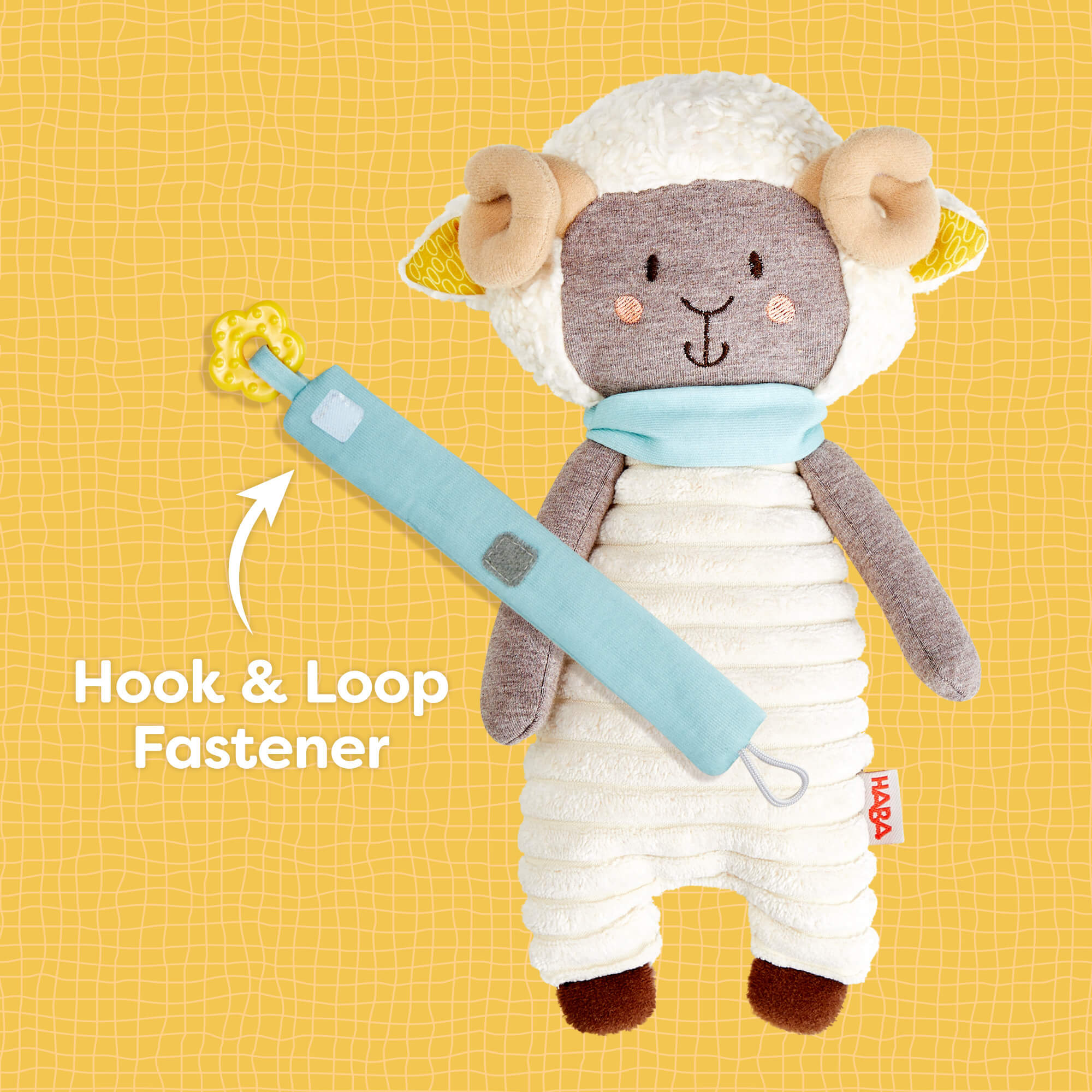 Plush toy sheep with a blue tool on a yellow background, featuring a hook and loop fastener.