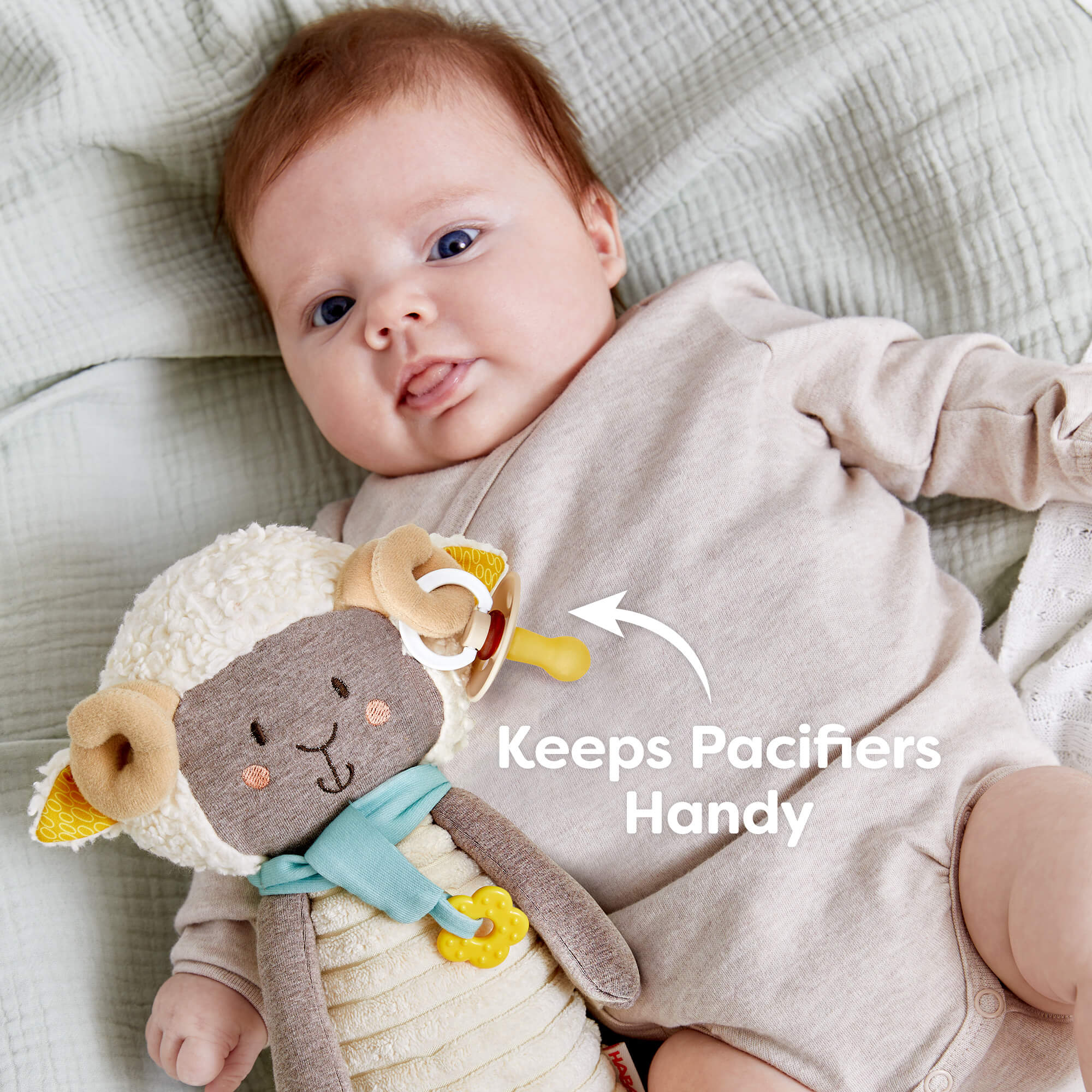Baby lying on a blanket with a plush toy and pacifier holder, labeled 'Keeps Pacifiers Handy'.