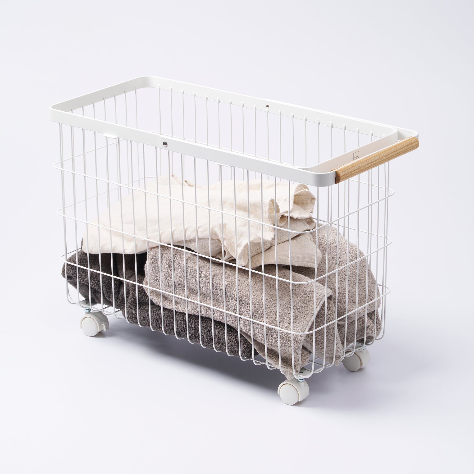 White wire laundry basket with wooden handle filled with clothes on a white background
