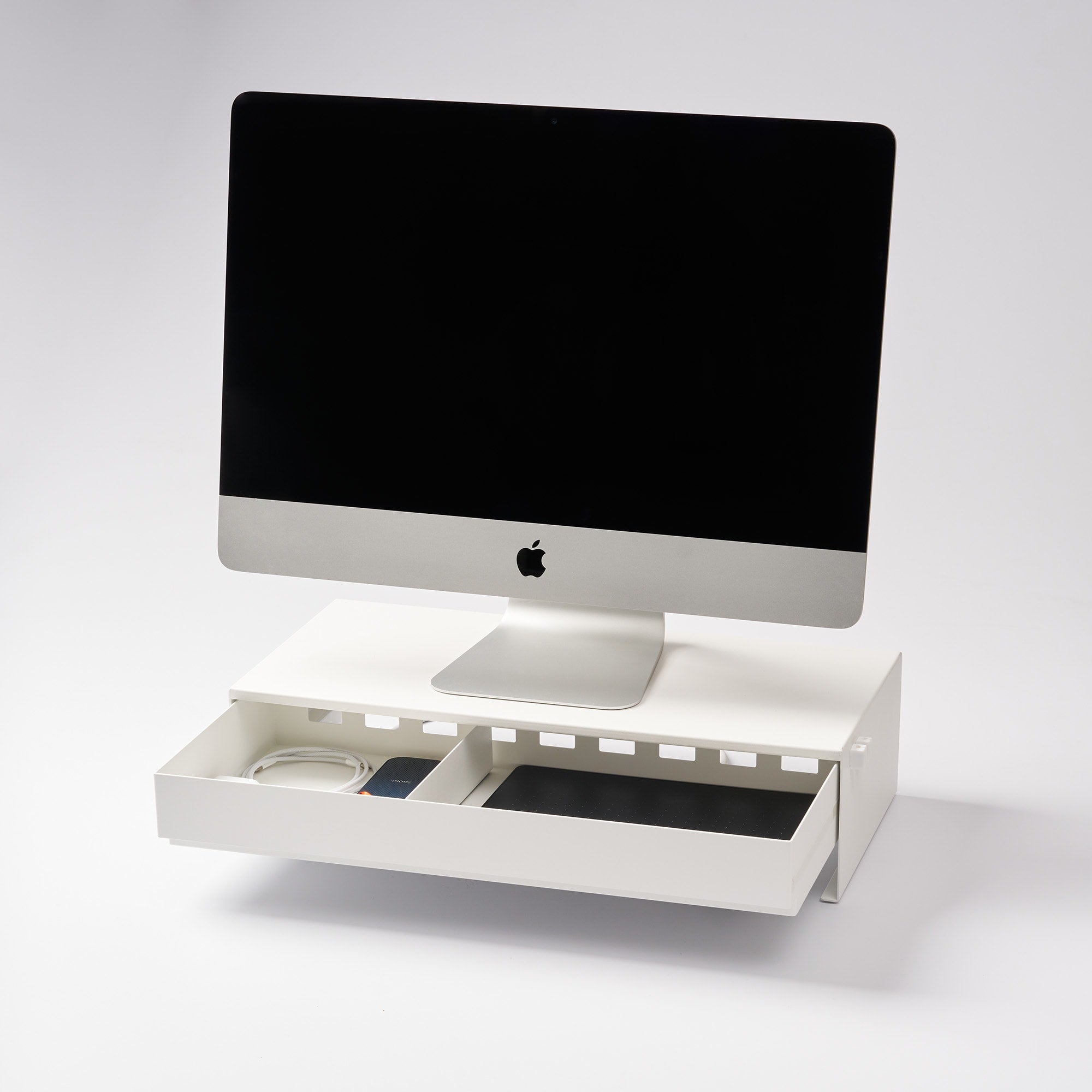 White computer desk with a monitor and accessories on a light gray background