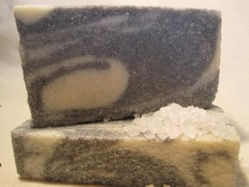 Two bars of charcoal soap sitting together.