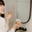 A woman in a bathrobe smiling and putting a toothpaste tablet into her mouth and smiling.