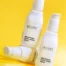 An image of 3 bottles of Acure Brightening Super Greens Serum on a yellow background