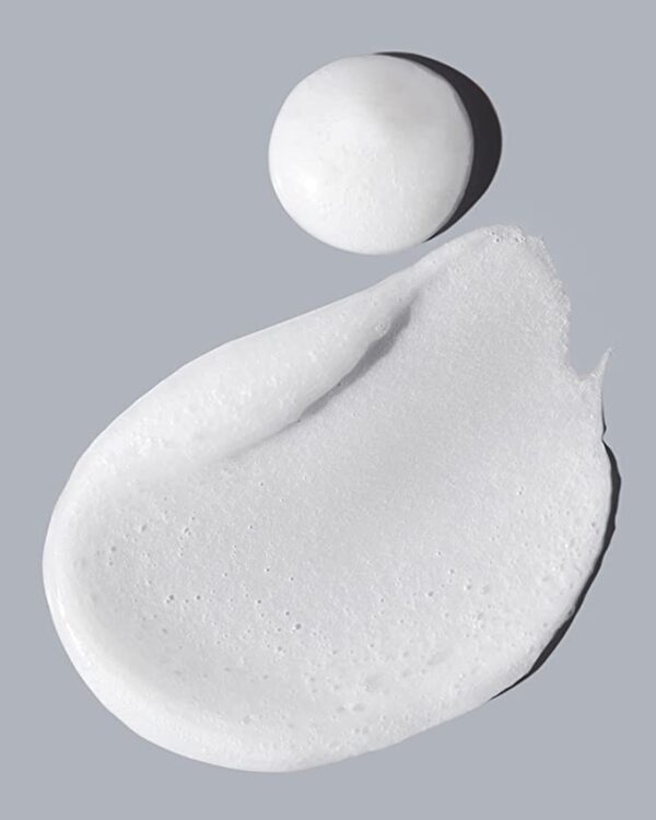 A dab of white Acure Resurfacing Glycolic & Unicorn Root Natural Face Cleanser on a dark grey background.