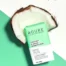 An image of Acure Natural Shampoo Bar sitting in a piece of coconut on a green and white background