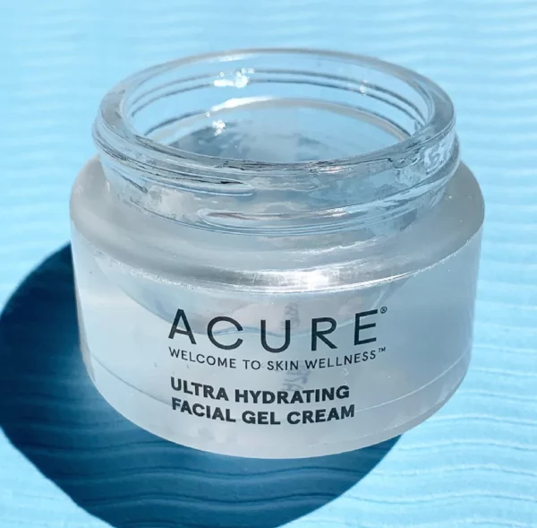 An open jar of Acure Ultra Hydrating Facial Gel Cream on a blue background.