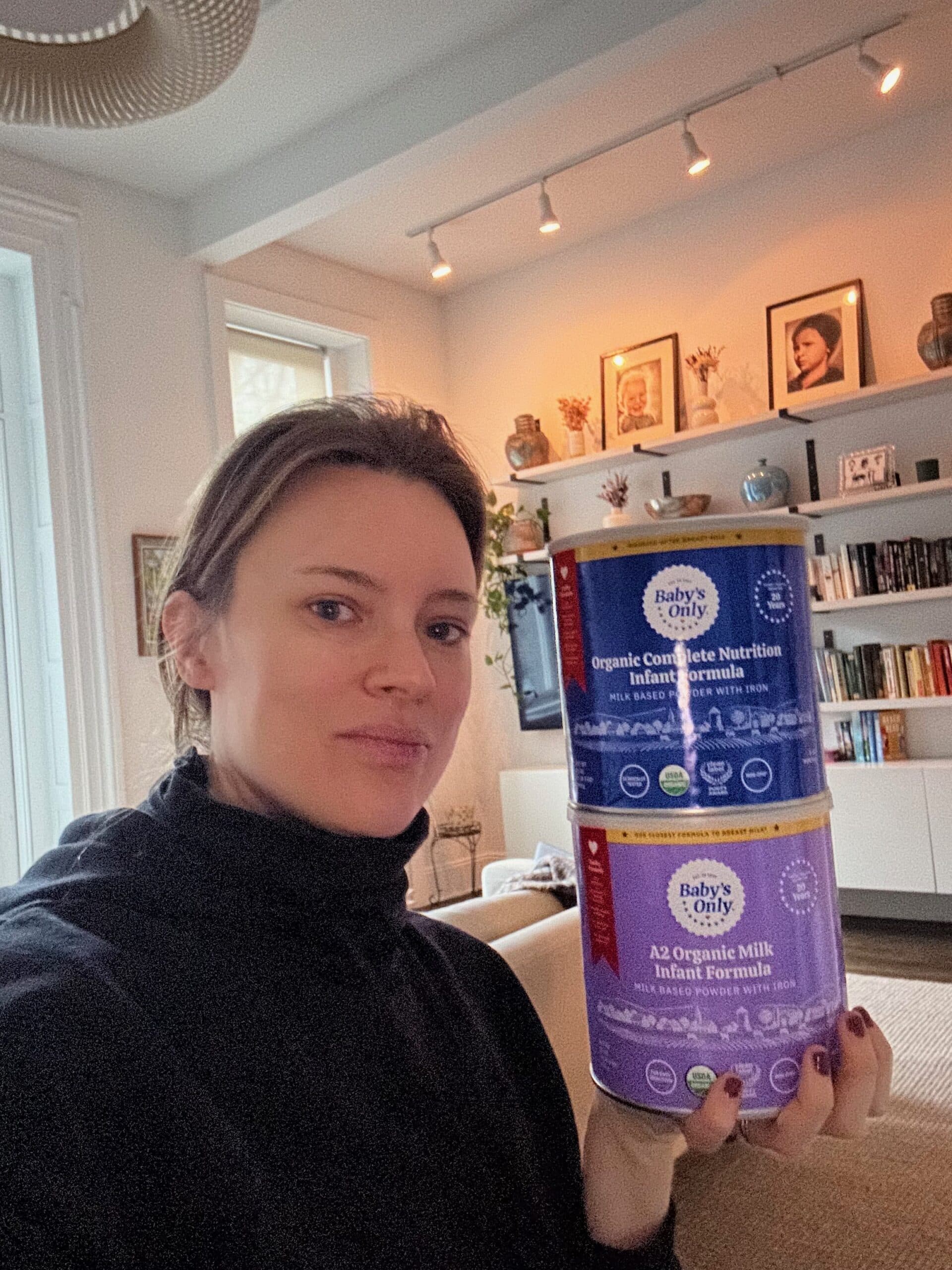 Maia from Gimme the Good Stuff holds cans of Baby's Only healthy baby formula