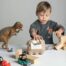 A young boy playing with dinosaur toys and beeswax crayons.