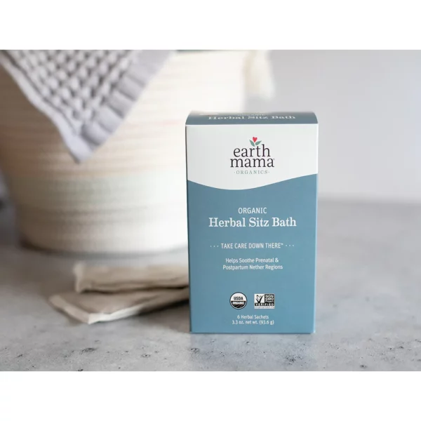 A box off organic herbal sitz bath sitting on a bathroom counter in front of a wash cloth and bowl.