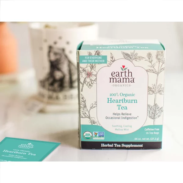 A box of Earth Mama Heartburn Tea sitting on a table next to a tea bag and a mug.