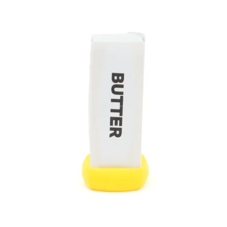 A stick of butter standing upright with a yellow silicone cap
