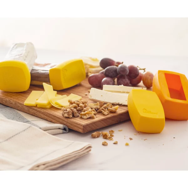 A cutting board full of different cheeses and nuts with silicone food covers for cheese in yellow colors.