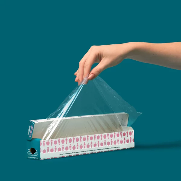 A hand pulling out a sheet of Full Circle Compostable Cling Wrap on a green background